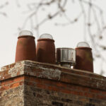 Bird protected chimney pots on red brick stack